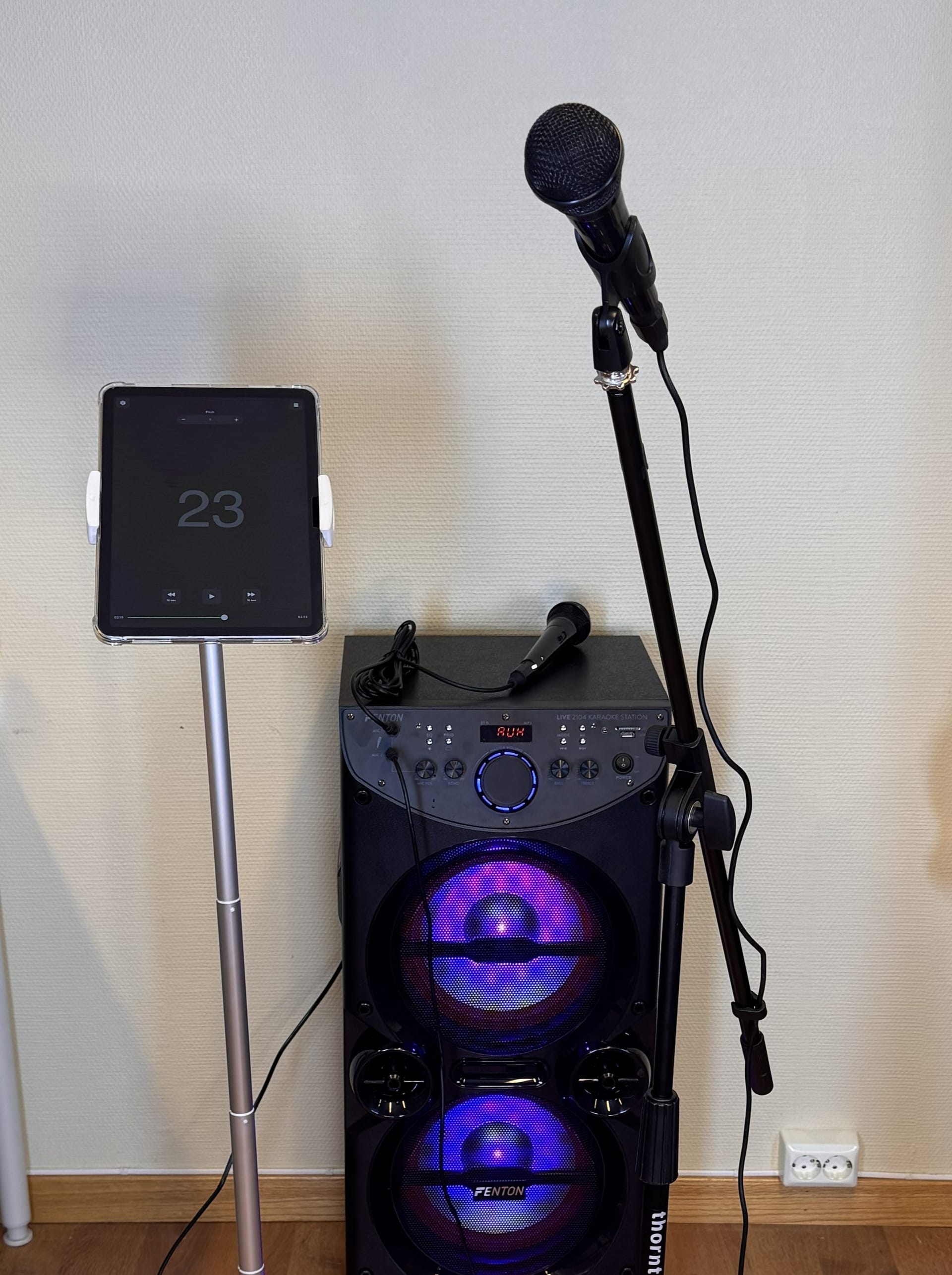 Karaokeanlegg med iPad på stativ, høyttaler og to mikrofoner
