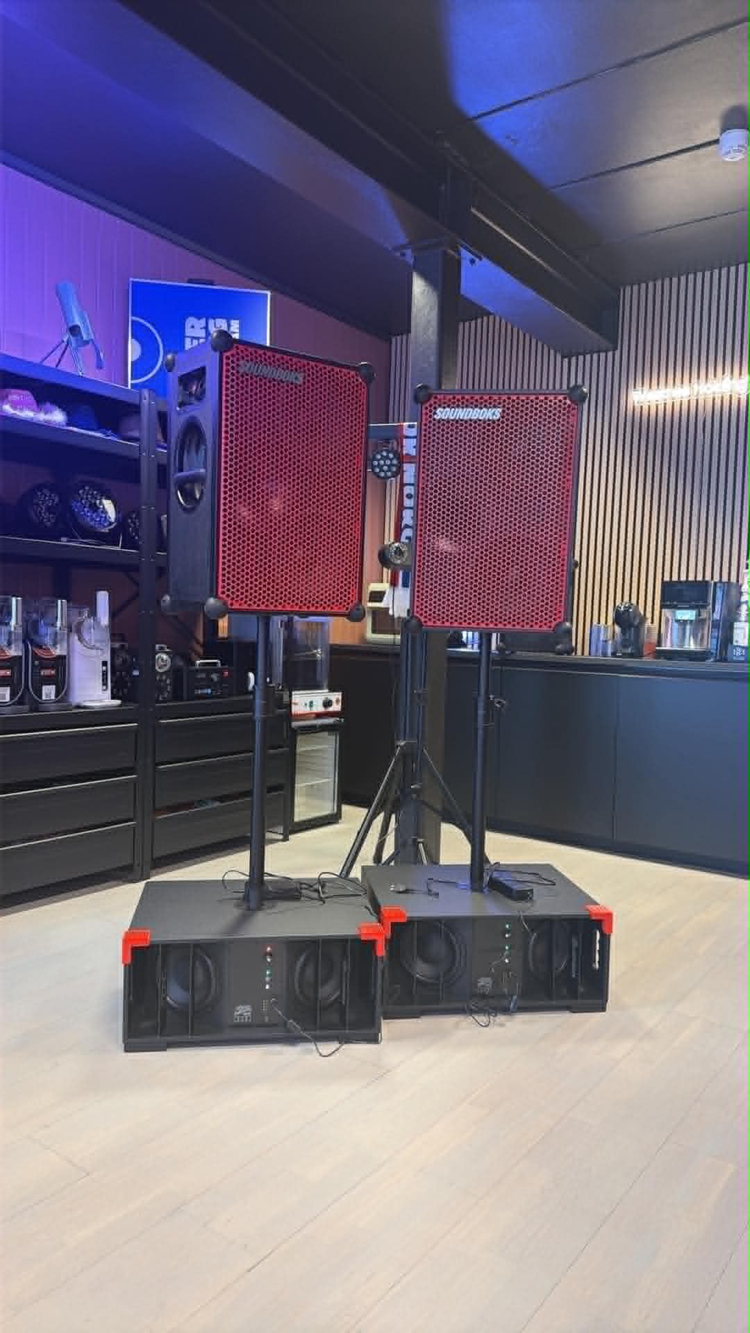 To Soundboks på stativ over to batteridrevne subwoofere