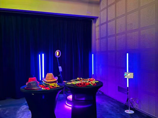 Lysrør i blått og lilla rammer inn rekvisittbord og photobooth